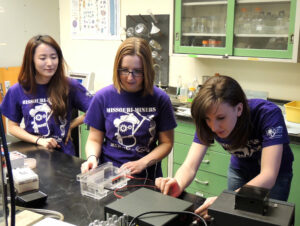 From left: Hannah Kim, Kelsey Crossen and Katherine Nelson prepare to conduct a gel electrophoresis. Photo by Kira Buckowing. 
