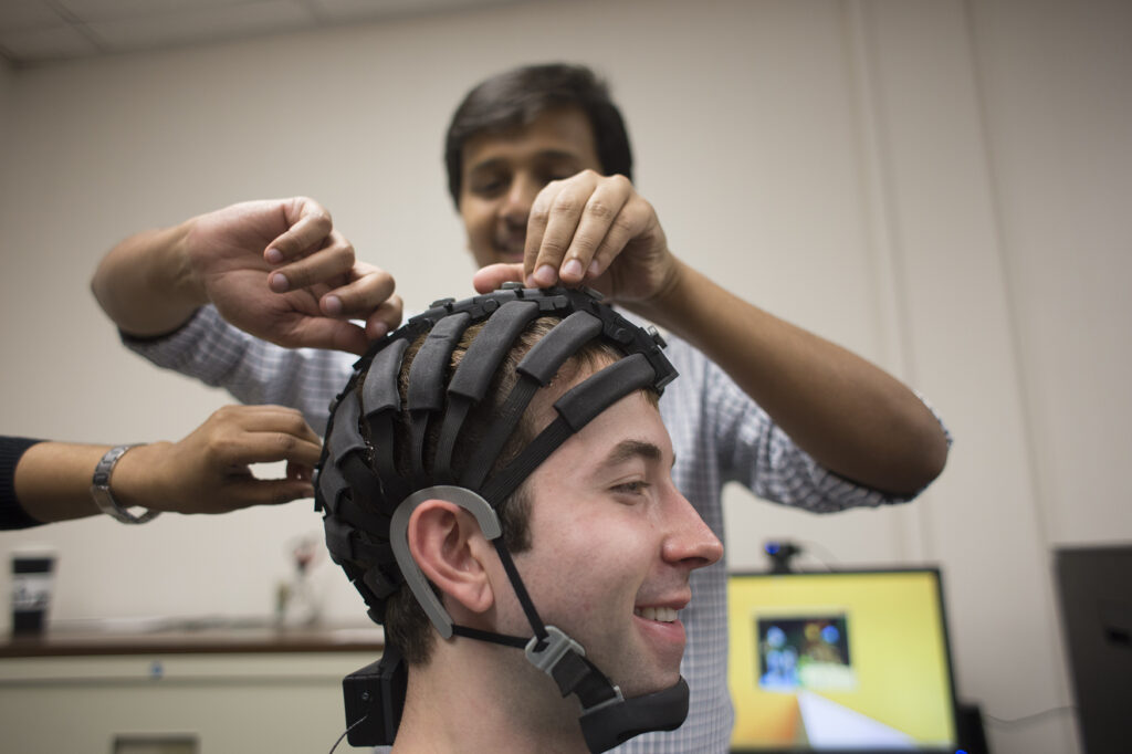 Nikhil Dusane, a graduate student in information science and technology, puts one of the business and information technology department's EEG headsets on Samuel Smith, a senior in information science and technology, in the university's Laboratory for Information Technology and Evaluation.