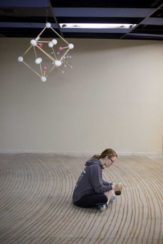 An S&T student paints tree rings on a concrete floor for what will become an environmental installation at Kaleidoscope Discovery Center.