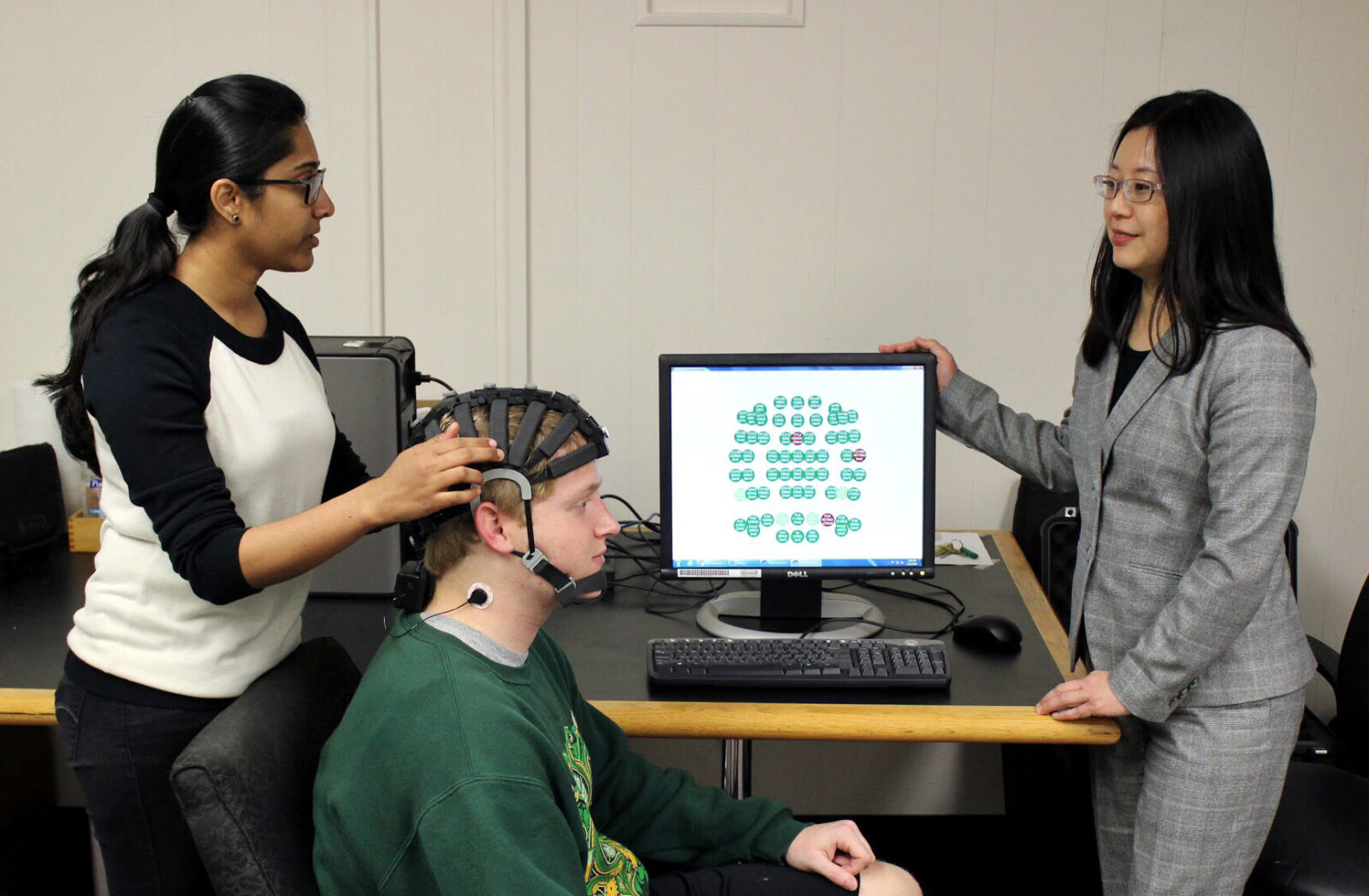 Tejaswini Yelamanchili affixes an electroencephalogram (EEG) headset on S&T student Bryan Fox. Fox, a senior in information science and technology, is aiding Yelmanchili's research on "flow" by playing the video game Tetris. With Yelmanchili and Fox is Yelmanchili's advisor, Dr. Fiona Nah.