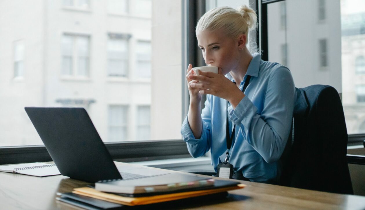 Photo of woman sipping a beverage at her computer