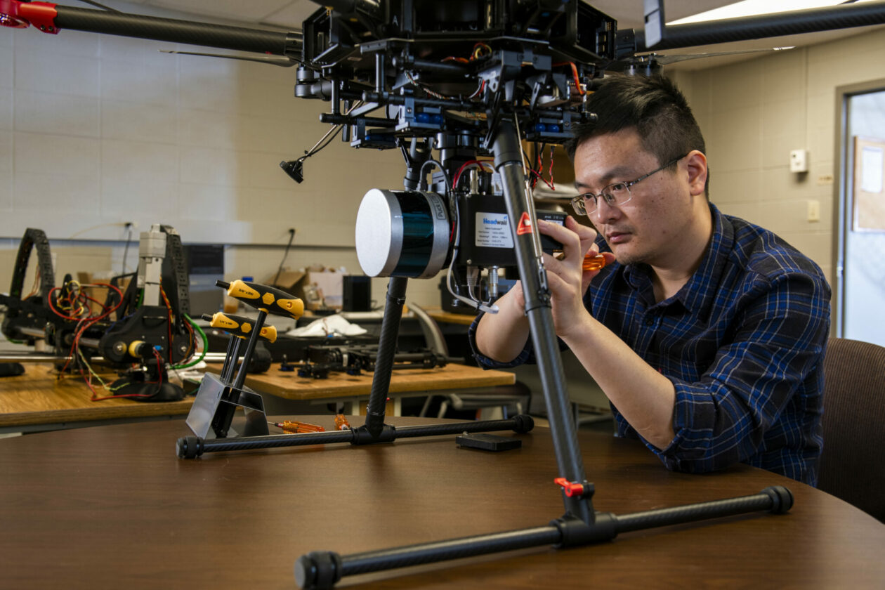 Photo of Xinzhe Yuan working on drone in lab