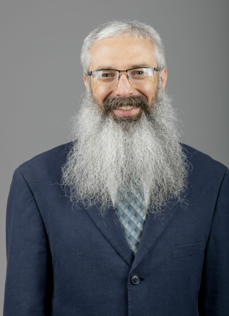 Photo of Dr. Jonathan Kimball with long beard, blue suit, white shirt and striped tie