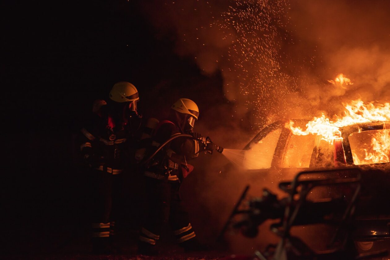 two firefighters battling vehicle fire