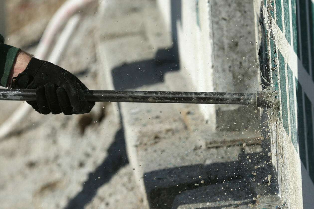 Gloved hand guides drill bit into rock slab