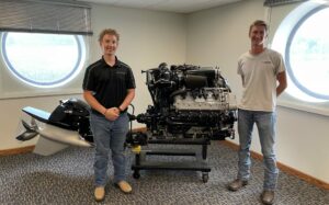 Brennen David, left, and Luke Mirly stand with a Mercury Marine engine in the company’s headquarters in Fond du Lac, Wisconsin. Photo courtesy of Luke Mirly.