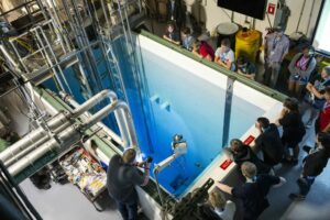 Campers peer into the pool that houses the university’s nuclear reactor core, which emits a blue glow when particles move faster than light in water. Photo by Blaine Falkena/Missouri S&T.