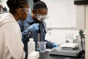 Two students wearing goggles and conducting research in chemistry lab at S&T