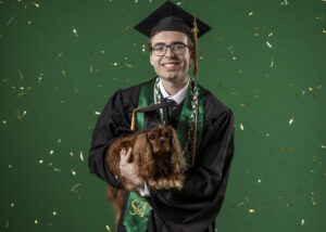 Matthew Stehlin celebrates his graduation from Missouri S&T with his mother Amy’s dog, Poppy. Photo by Michael Pierce/Missouri S&T.