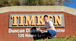 Missouri S&T recent graduate Duncan Bannon in front of the sign at the Timken Distribution Center.