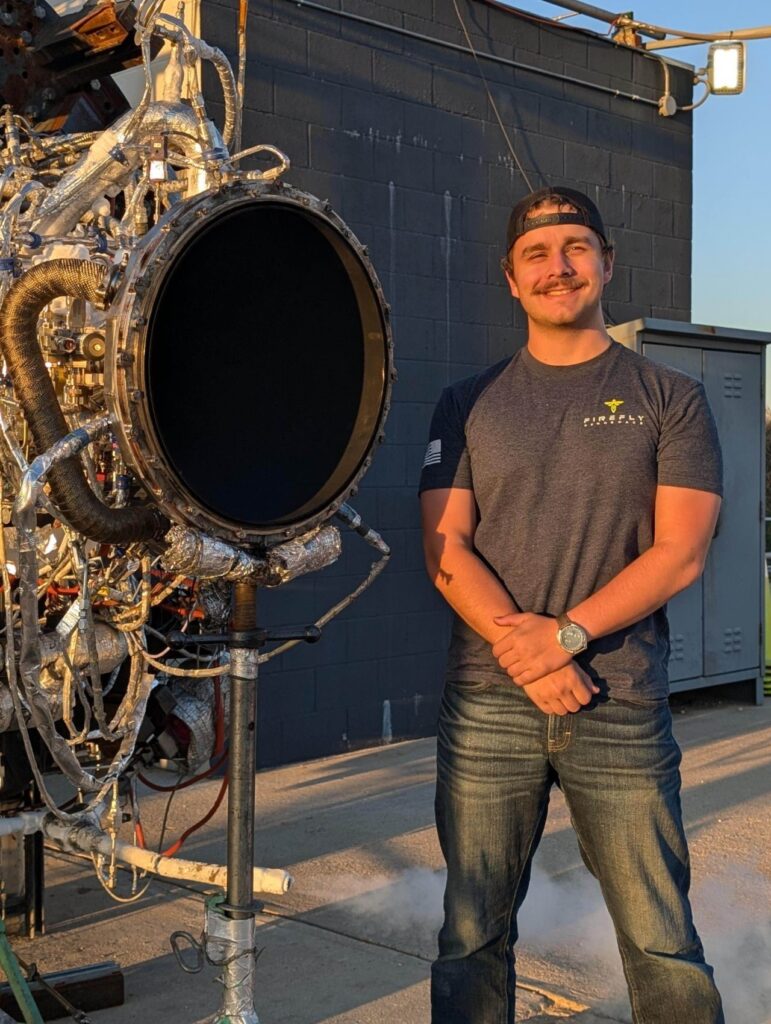 Nick Graham stands next to an engine on a test stand during his internship with Firefly Aerospace. Photo courtesy of Graham.