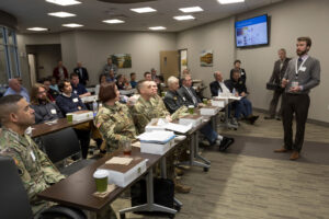 Classroom setting with a male teacher and several adult students dressed in military fatigues.