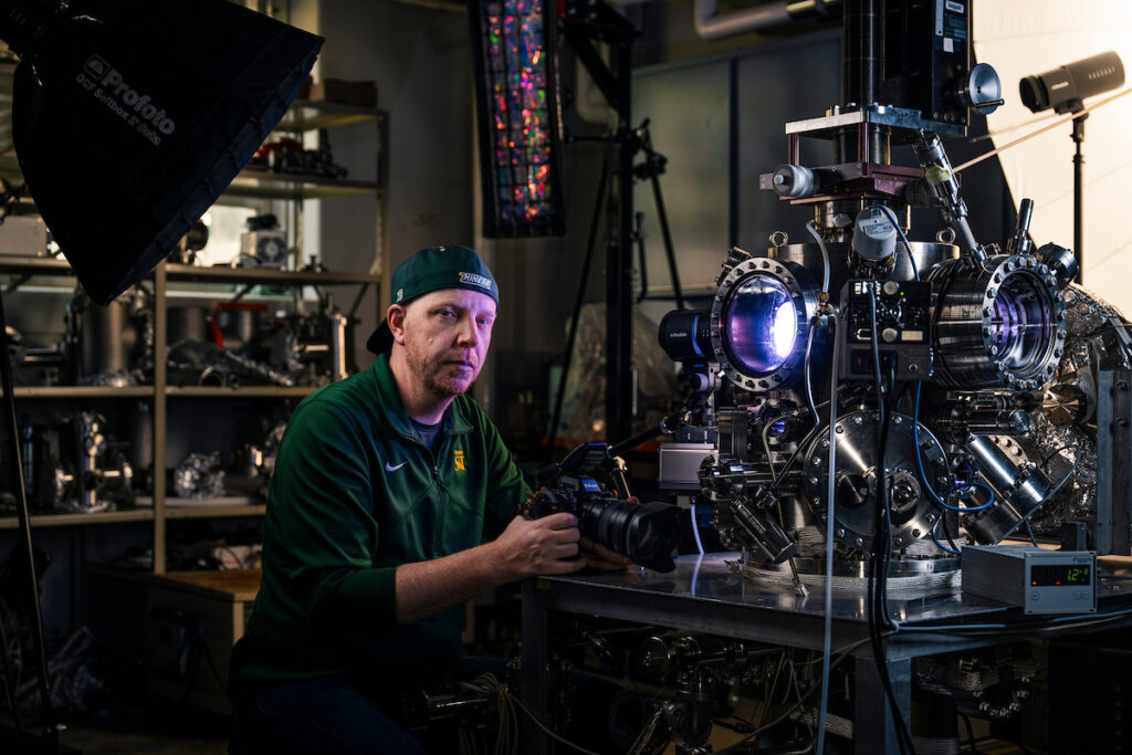 Man holds camera in room with science equipment