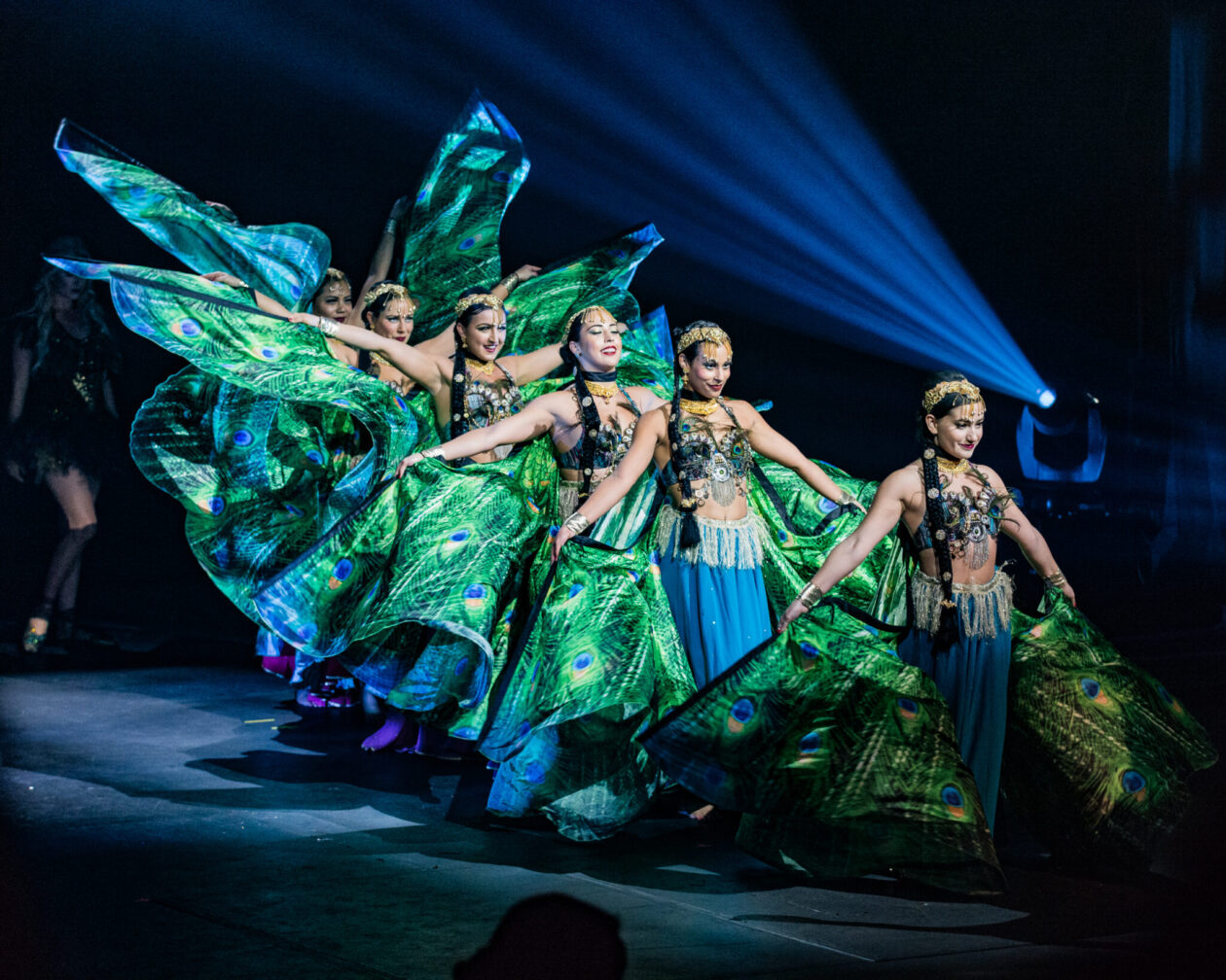 Six dancers in vibrant blue and green costumes perform during a Bollywood Live! show.