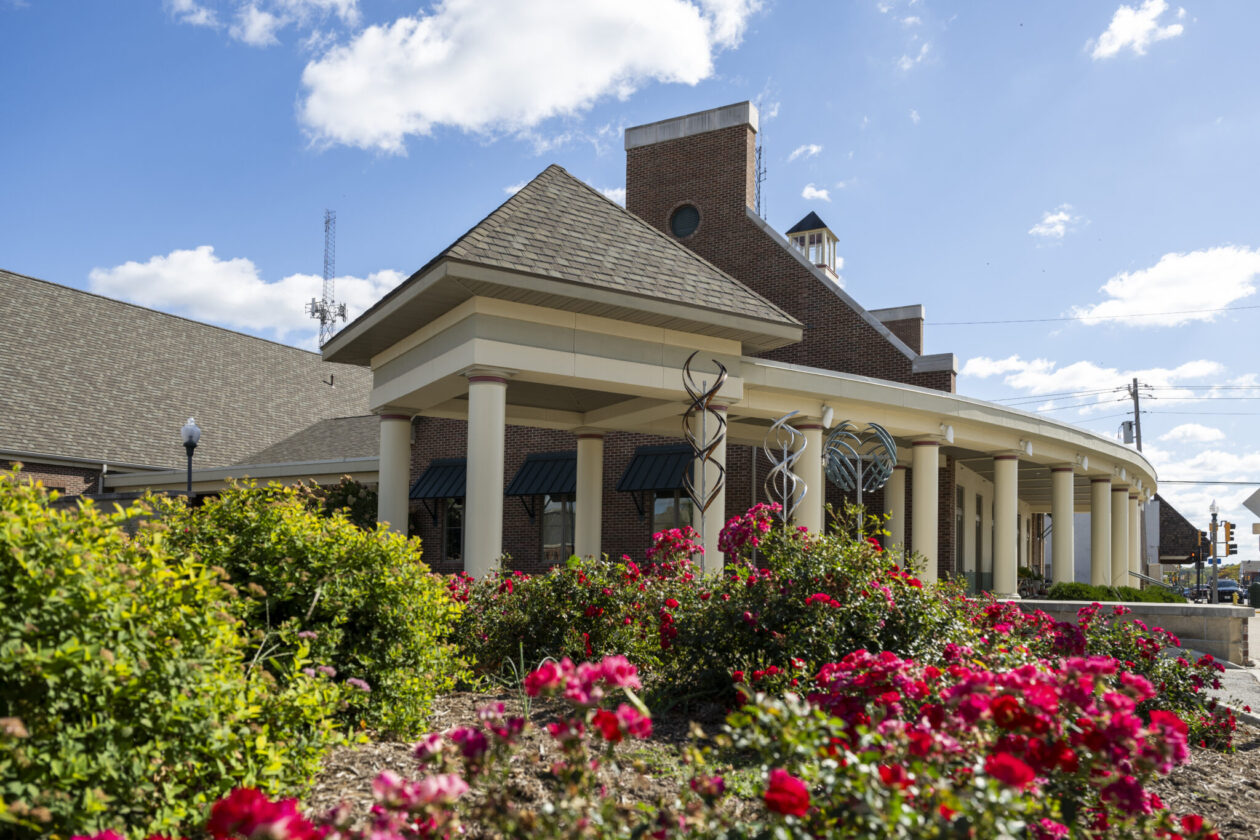 Hasselmann Alumni House, with red flowers in the foreground.