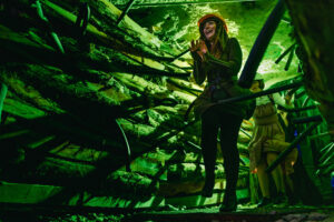 A person walking through Missouri S&T's haunted mine, and wearing a hard hat. A person in a dress/costume is following behind.