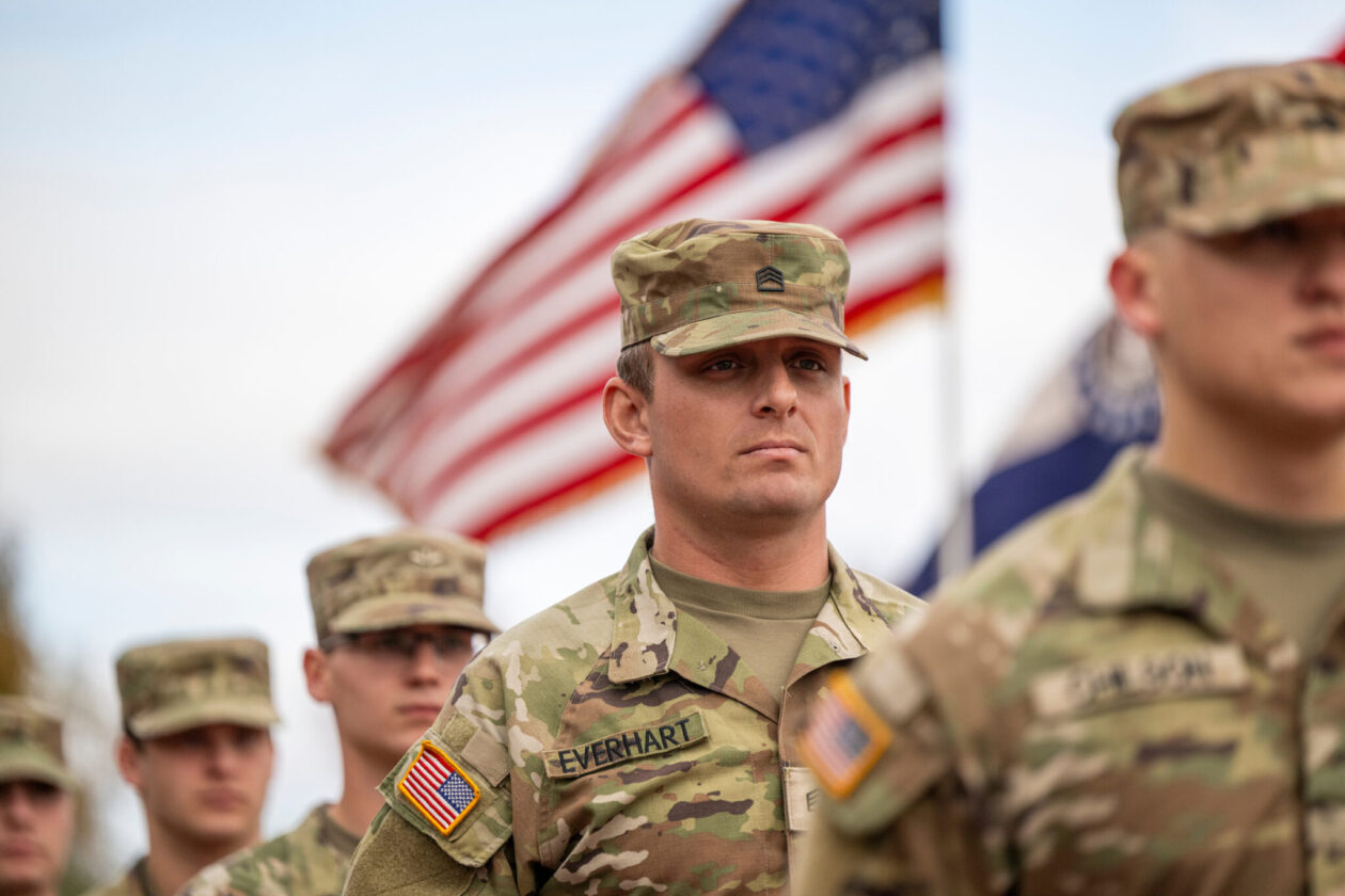 ROTC cadets in Army fatigues and American flag.