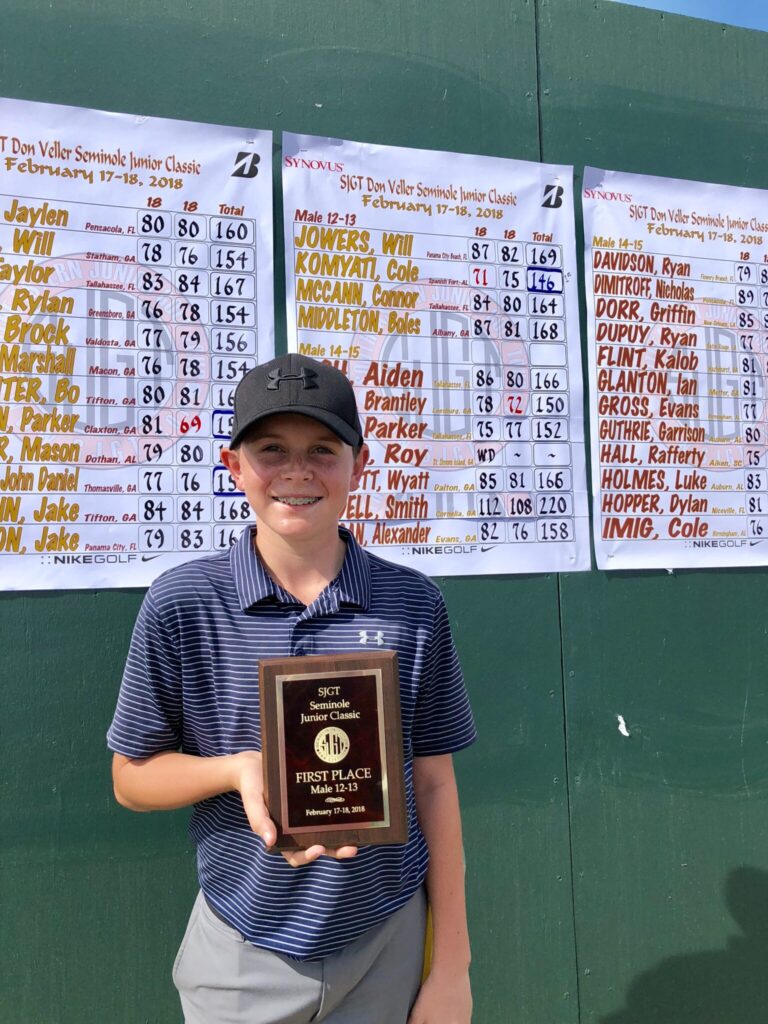 Cole Komyati holding up a first place golf award at a tournament he competed in as a child.
