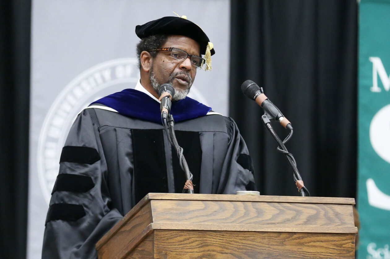 Dr. Harvest Collier speaks at a podium during a 2014 commencement ceremony.
