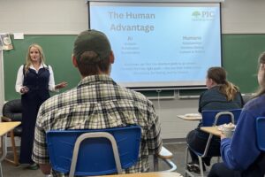 Presenter standing at front of class talking to students.