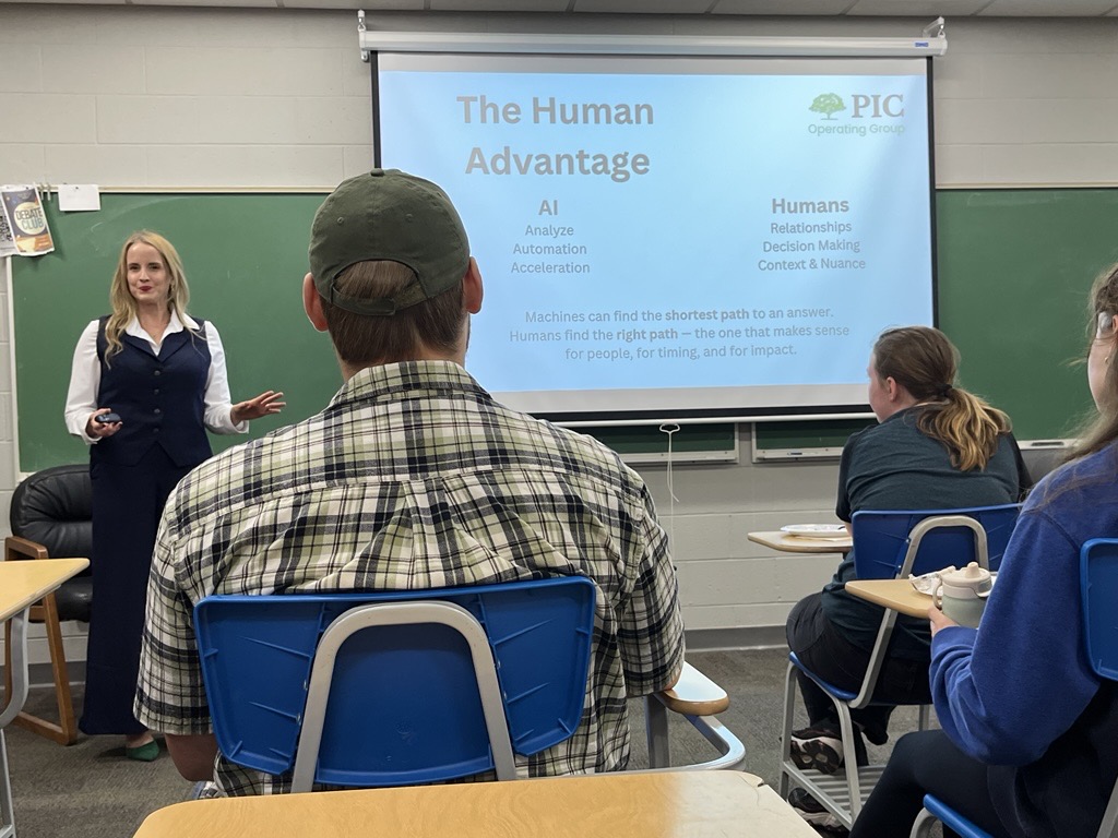 Presenter standing at front of class talking to students.