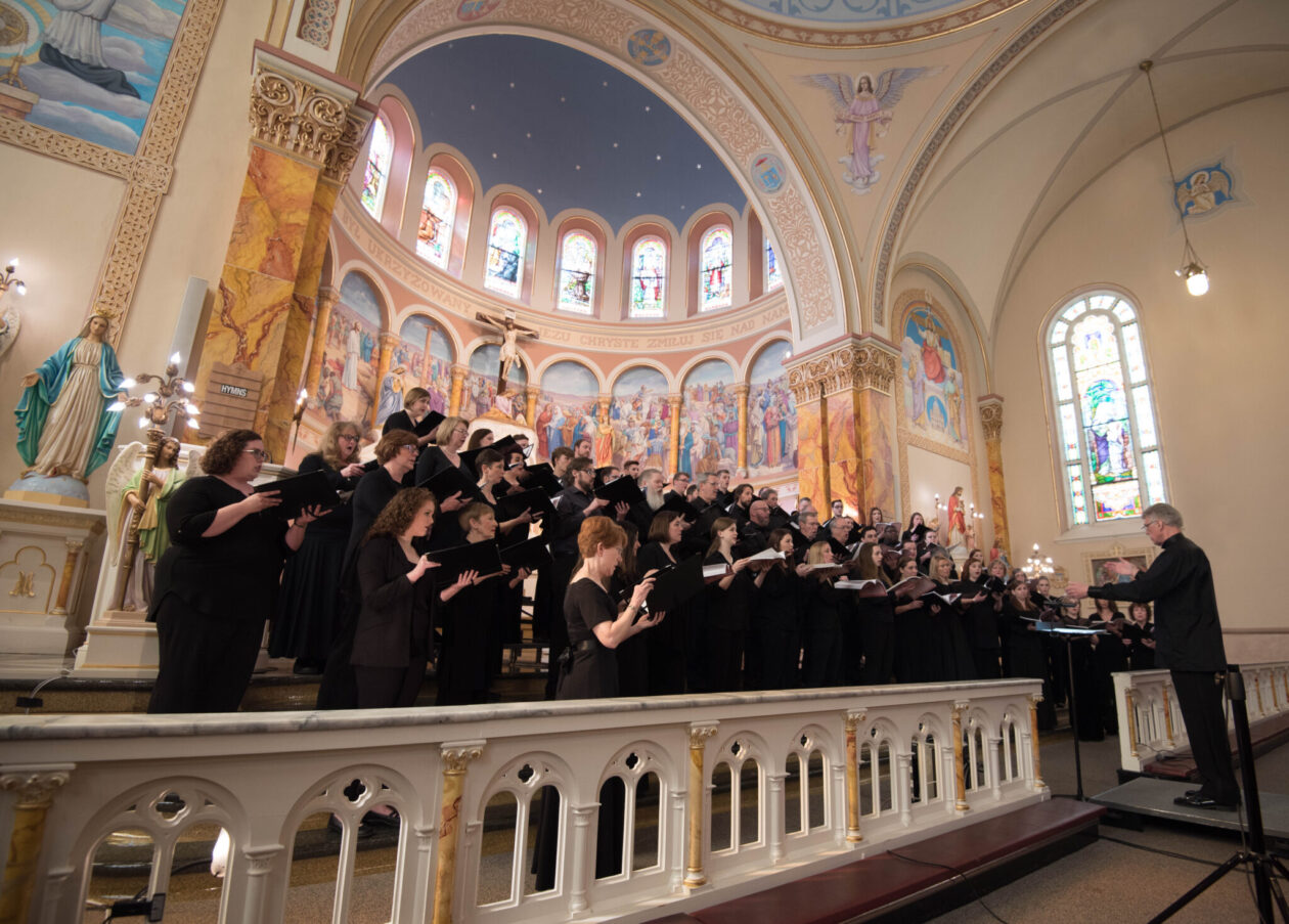 The Bach Society of Saint Louis, a group of singers dressed in black, during a performance in a church.