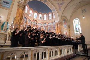The Bach Society of Saint Louis, a group of singers dressed in black, during a performance in a church.