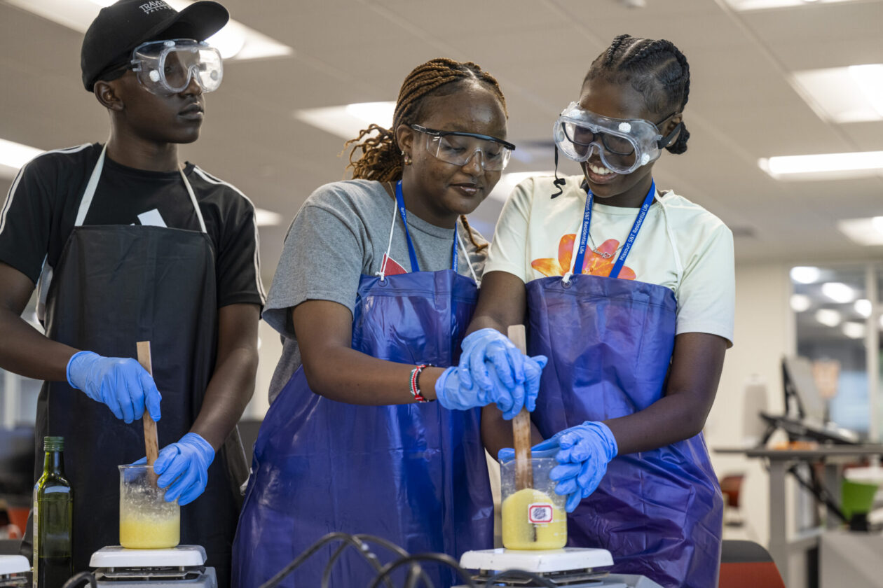 Three summer camp students gather around a science lab at the S&T campus.