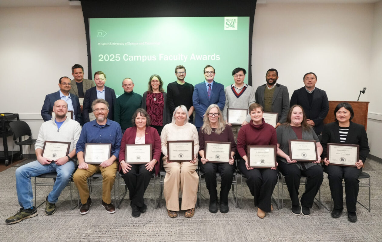 Faculty awardees pose for a photo, with eight seated in a row and ten standing behind them.