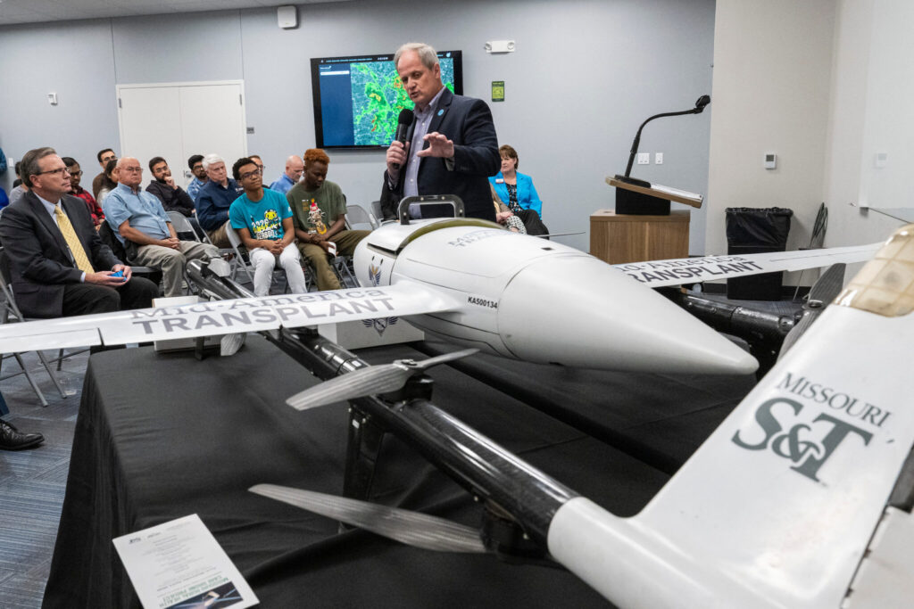 Speaker gestures toward drone.