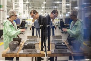 Engineer shows guest manufacturing equipment. 