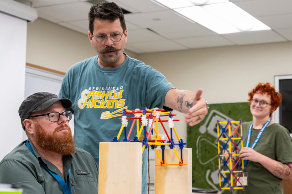 Three teachers testing bridge designs in classroom.