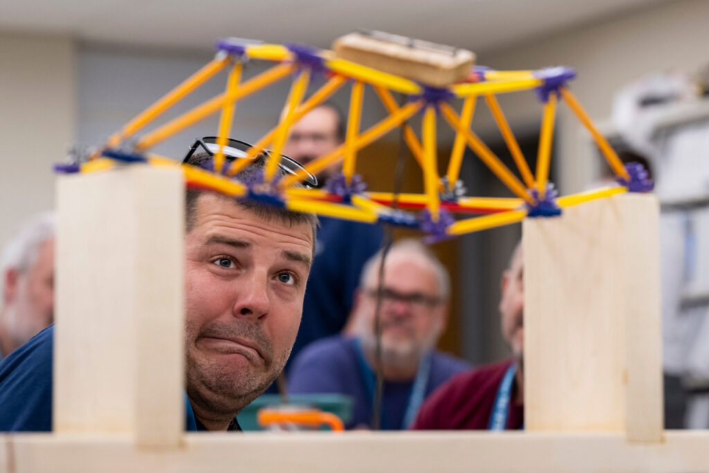 Teacher makes fearful face as it appears a toy bridge will collapse under the weight of a load.