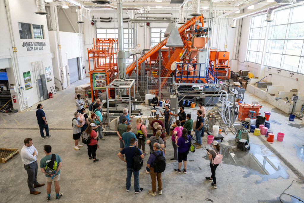 Group of people in large high-bay area with huge machinery.