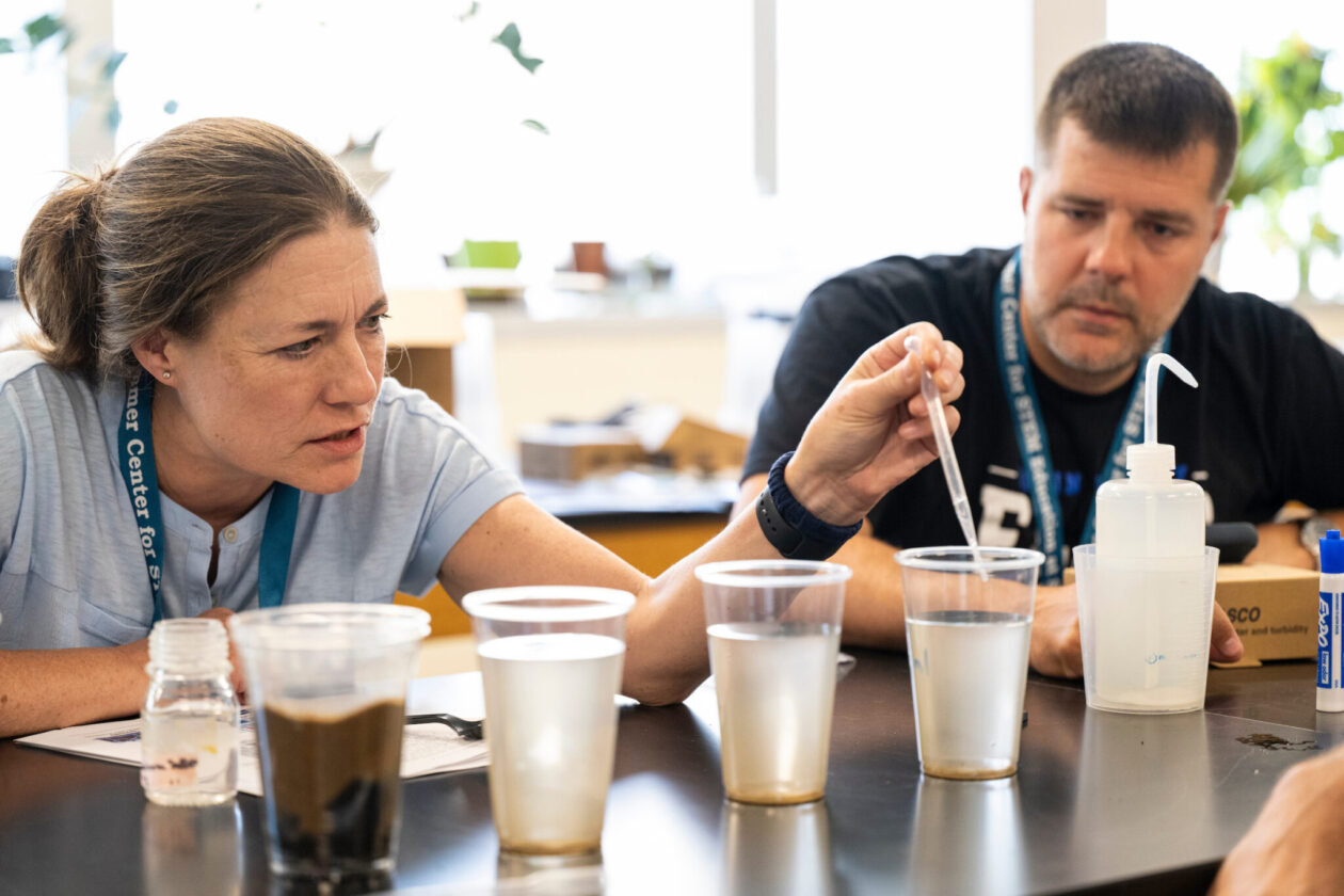 Person places pipette above clear cup of water. Four cups are lined up with varying levels of murkiness.