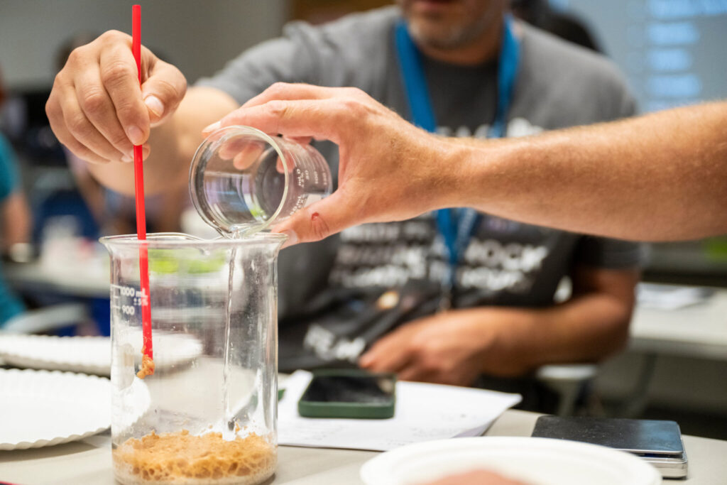 Closeup of hands and beaker.